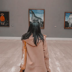 Rear view of woman standing against wall in museum