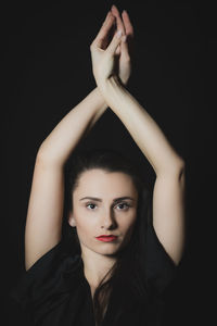 Portrait of young woman against black background