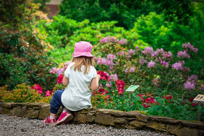 Rear view of woman with pink flowers against plants