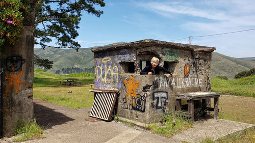 Portrait of woman standing in abandoned house against sky