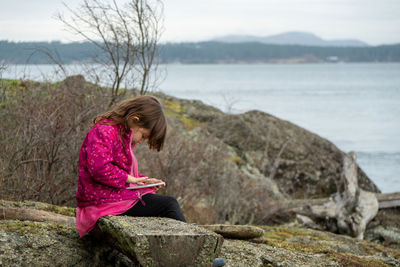 Rear view of girl sitting on rock
