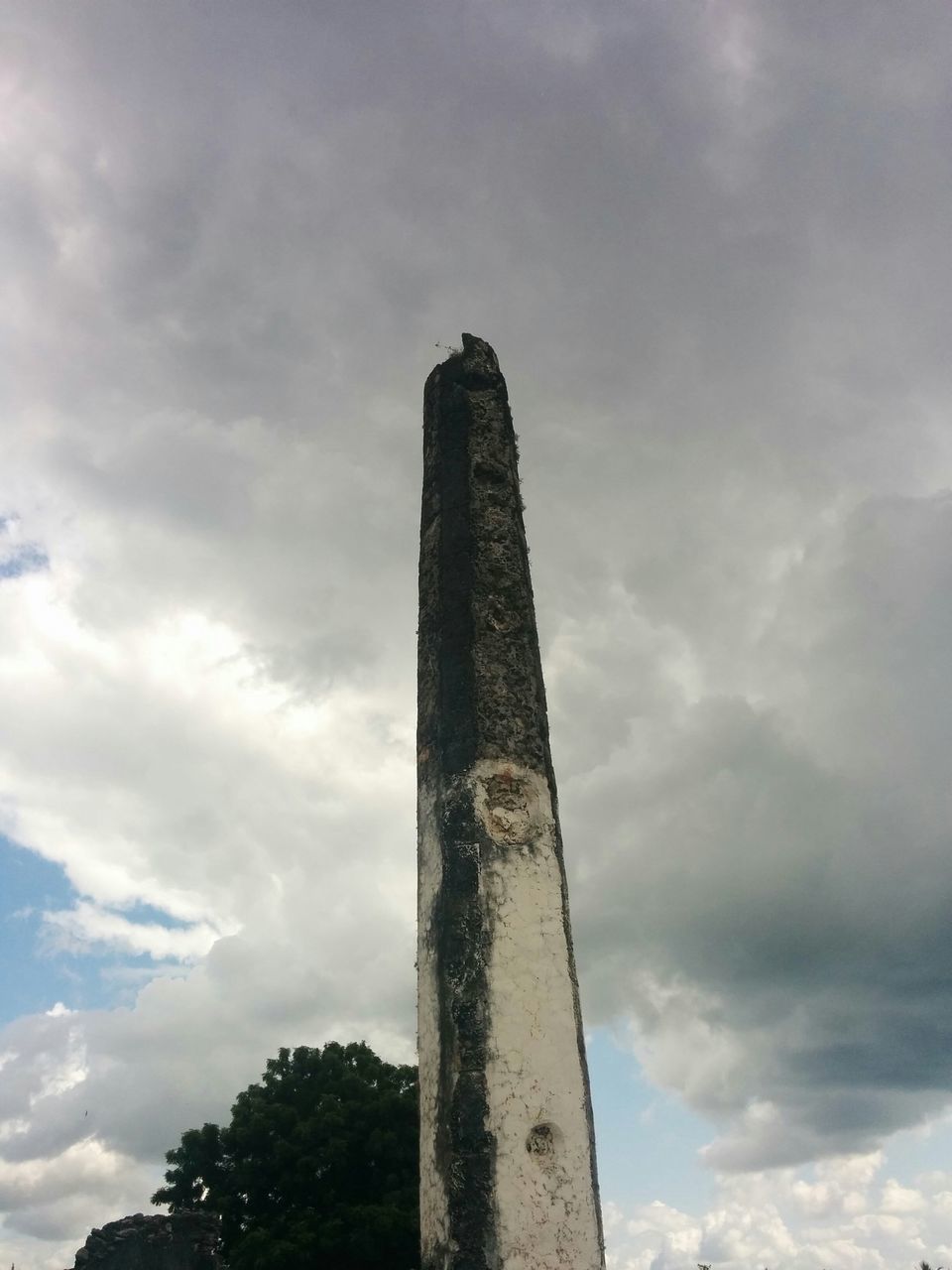 low angle view, sky, architecture, built structure, cloud - sky, cloudy, cloud, building exterior, tree, tower, tall - high, day, no people, outdoors, tall, old, history, nature, smoke stack, architectural column