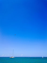 Sailboat sailing on sea against clear blue sky