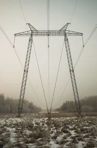 Low angle view of electricity pylon on field against sky