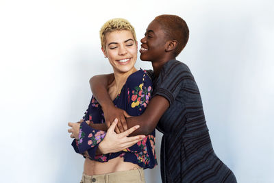 Cheerful lesbian couple embracing against white background