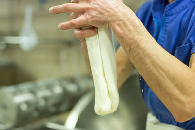 Midsection of man preparing mozzarella cheese in factory