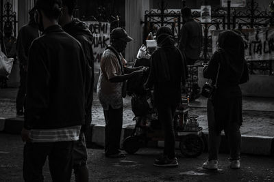 Rear view of people walking on sidewalk in city