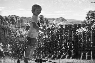 Playful boy enjoying in sprinkler