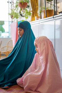 Cute girls in hijab praying at home