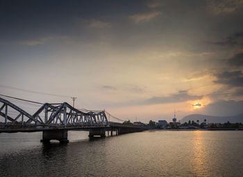 Bridge over river against sky during sunset