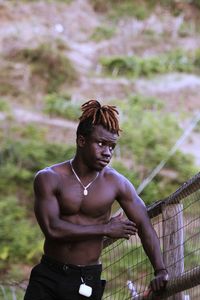 Portrait of shirtless young man looking away standing in forest