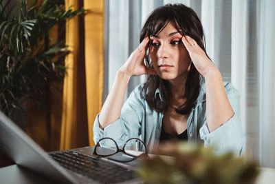 Frustrated young woman by laptop in office