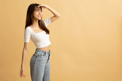 Young asian girl dress in white shirt and jeans ready to travel on vacation on yellow background