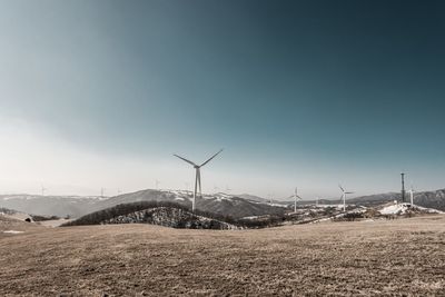 Wind turbines on field at eco green campus against clear sky