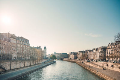 Canal passing through city buildings against sky