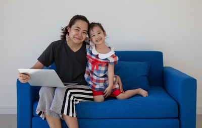 Full length of a smiling woman sitting on sofa