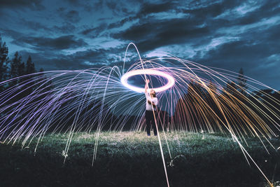 Woman standing amidst wire wool on field against sky