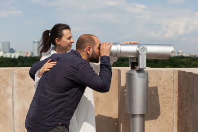 Rear view of man photographing against sky