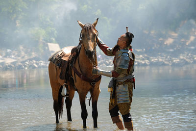 Side view of man with horse in lake