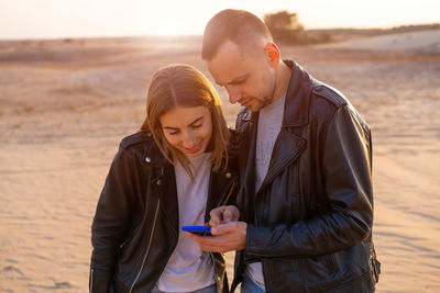 Young man using phone while standing on beach