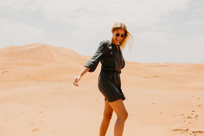 Portrait of smiling young woman standing on desert