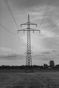 Low angle view of electricity pylon on field against sky