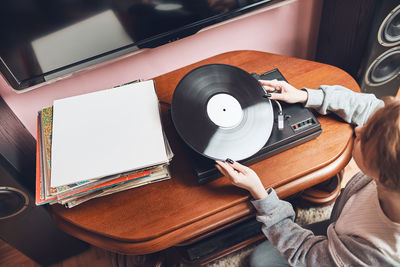 Young woman listening to music from vinyl record player. retro and vintage style. hobby and passion