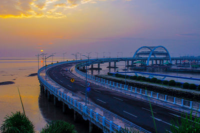 Bridge over beach against sky at sunrise