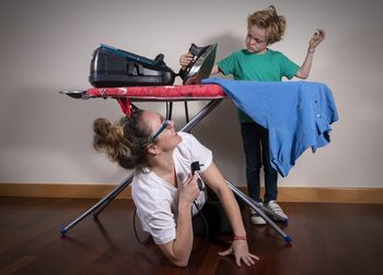 Rear view of friends sitting on wooden floor at home