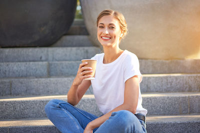 Portrait of smiling young woman sitting on staircase
