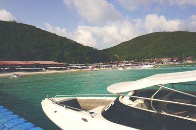 Boats moored in sea against cloudy sky