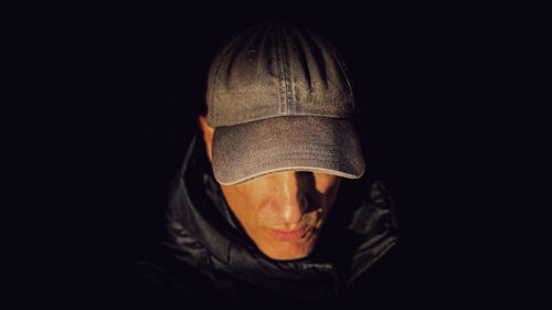 Low section of woman wearing hat against black background