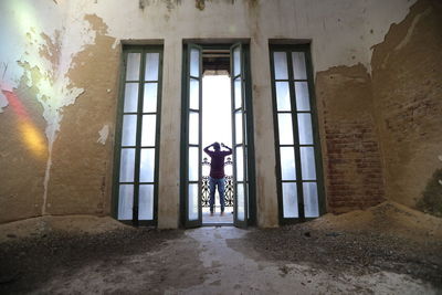 Man standing by window in abandoned building