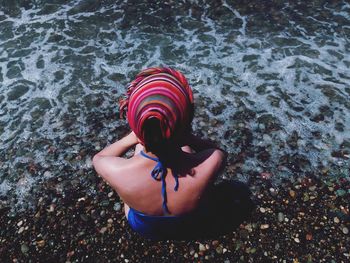High angle view of young woman sitting on shore at beach