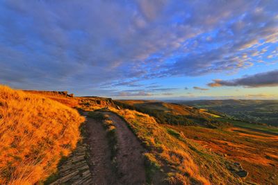 Scenic view of road amidst land against sky during sunset