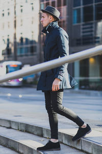 Side view of man walking down steps in city