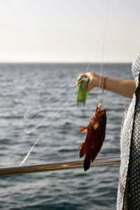 Rear view of woman holding fish in sea