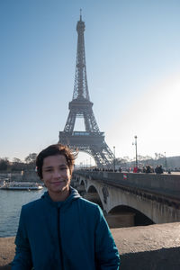 Boy posing to the camera with the eiffel tower in background.