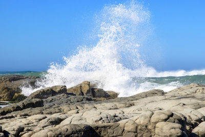 View of waves breaking against clear blue sky