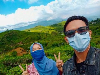 Portrait of young woman wearing sunglasses against mountain