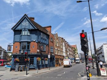People walking on street by buildings against sky