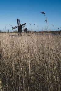 Traditional windmill on field against clear blue sky