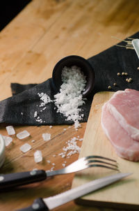High angle view of salt and meat on wooden table