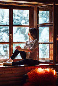 Woman sitting on table by window