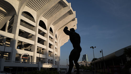 Low angle view of silhouette man standing against buildings in city