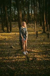 Full length portrait of smiling young woman standing in forest