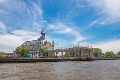 Buildings by river against sky