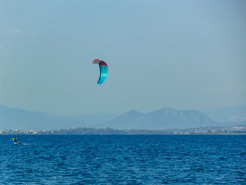 Person paragliding over sea against sky