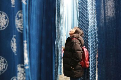 Young girl surrounded by indigo dyeing. looking up to the light with joyful and charming smile .