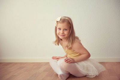 Portrait of ballet dancer sitting on wooden floor